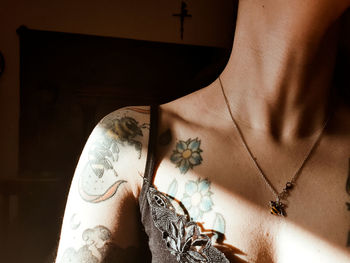 Midsection of sensuous woman with tattoo at home