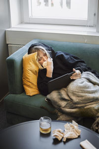 Ill woman on sofa using digital tablet