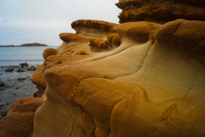 Rock formation on beach against sky