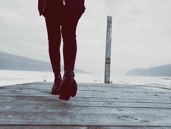 Low section of man standing on jetty against sea