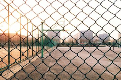 Basketball hoop seen through chainlink fence against sky