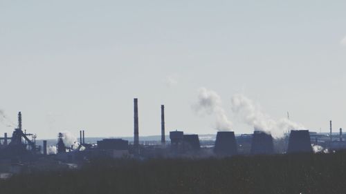 Smoke emitting from factory against sky