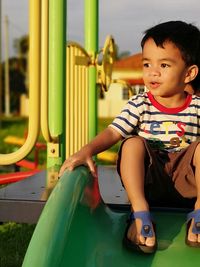 Cute boy sitting on slide at playground