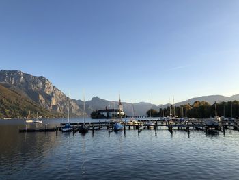 Sailboats moored in harbor against clear sky