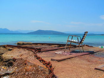 Deck chairs on beach against clear blue sky