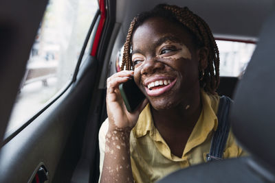 Happy young woman talking on smart phone in car