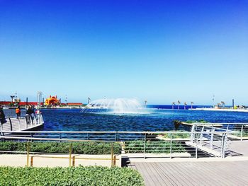 People in water against clear blue sky