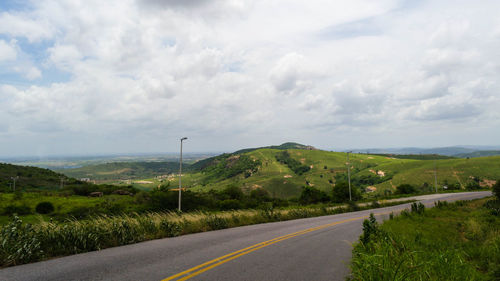 Road passing through landscape against cloudy sky