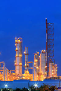 Illuminated factory against blue sky at night