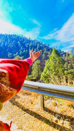 Midsection of person with red umbrella against blue sky