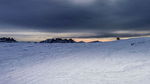 Snow covered landscape against the dolomites and bad weather sky with some pale light