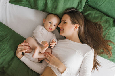 Mother's day. the mother lies on the bed and hugs the happy baby son at home