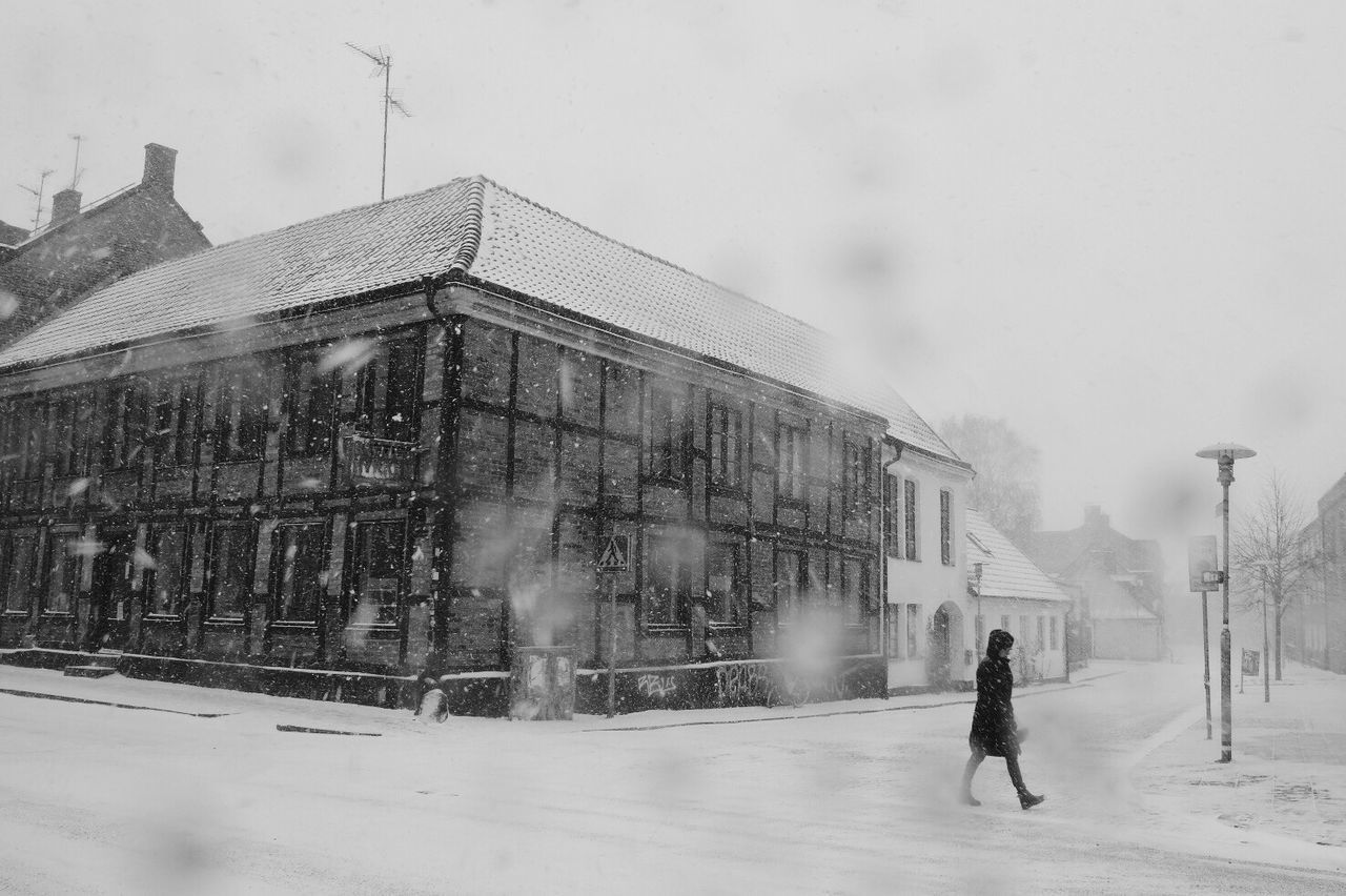 MAN CYCLING ON SNOW COVERED CITY IN WINTER