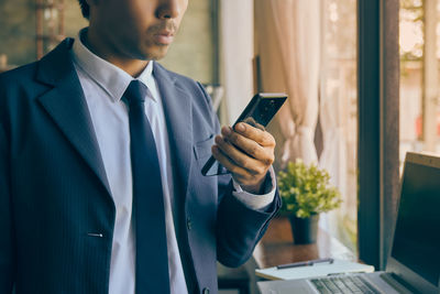 Midsection of man using mobile phone
