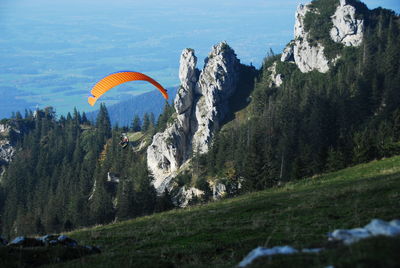 Person paragliding over grassy field