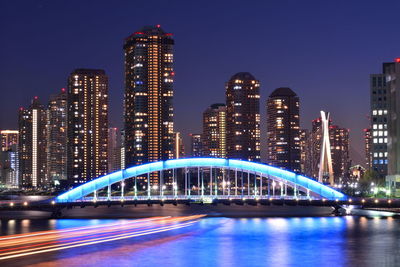 Illuminated bridge and buildings against sky at night