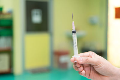 Cropped hand of doctor holding syringe in hospital