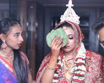 Bride holding leaves by girl and man during wedding