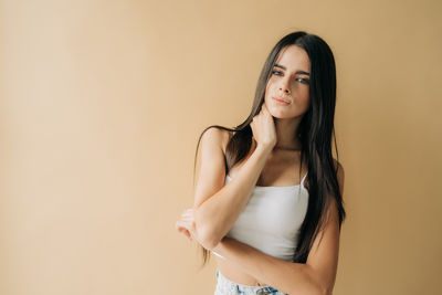 Portrait of young woman standing against wall