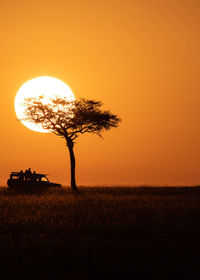 Silhouette tree on field against orange sky