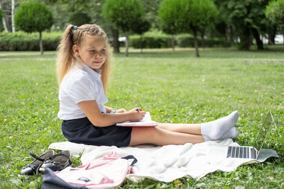 Portrait of young woman using laptop while sitting on field