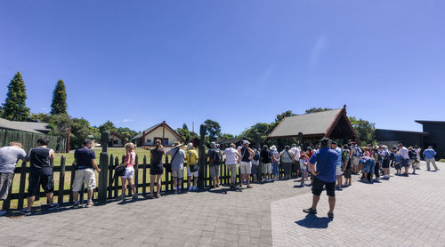 People walking on street against blue sky