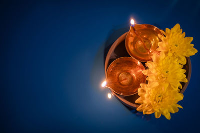 Directly above shot of illuminated candle against blue background