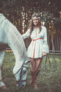 Portrait of young woman with horse on field