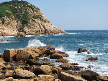 Scenic view of rocks on beach against clear sky