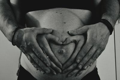 Husband and wife making heart shape with hands on pregnant woman abdomen