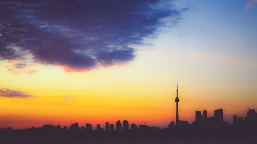 Silhouette of buildings against cloudy sky during sunset