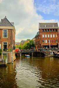 Buildings by canal against sky