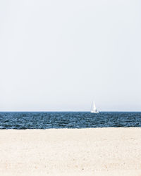 Sailboat sailing on sea against clear sky