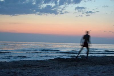 Silhouette man on beach against sky during sunset