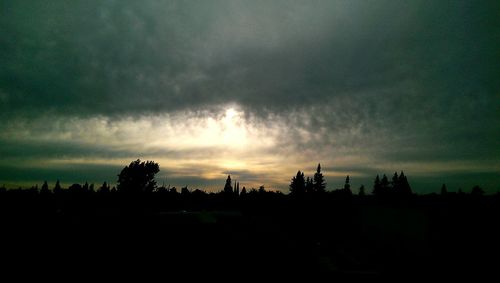 Silhouette of trees against cloudy sky