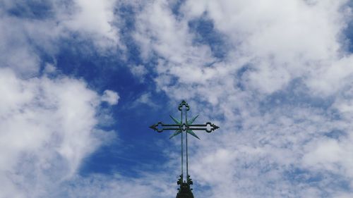 Low angle view of weather vane against cloudy sky