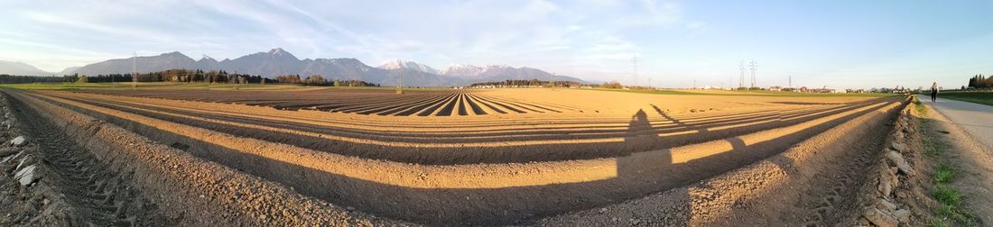 Panoramic view of agricultural field against sky