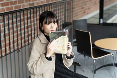 Young woman using mobile phone while sitting on table