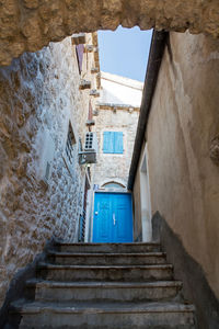 Blue old wooden door in a stone house with stairs in montenegro