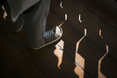 Low section of man standing on hardwood floor
