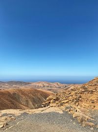 Scenic view of desert against clear blue sky