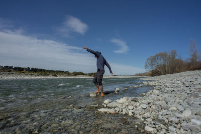 Man standing on rock in sea against sky during winter