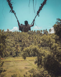 Rear view of man on field by trees against sky