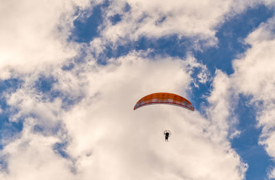 Low angle view of person paragliding against sky