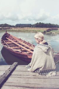 Young woman on boat moored in lake against sky