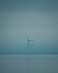 Wind turbines in sea against sky