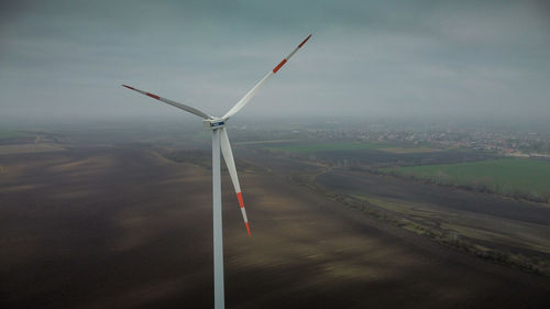 Wind turbines on landscape against sky