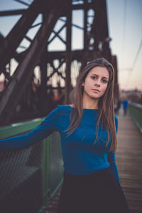 Young woman in blue long sleeve shirt on a street. urban sunset portrait