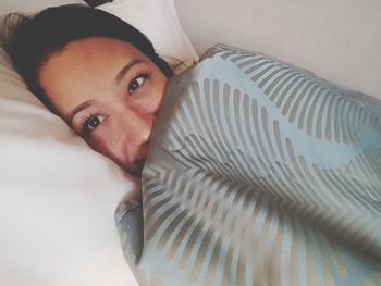 High angle portrait of woman relaxing on bed at home