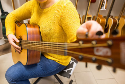 Midsection of woman playing guitar at store